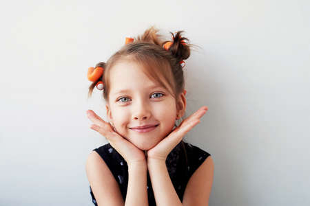 A 6-year-old girl with curlers on her head. The pursuit of beauty.Childrens joys. Isolated on a...