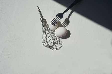 Egg with shadow from the fork. Minimalism. Cooking pastries, omelets. Easy.Whisk for whipping.の写真素材