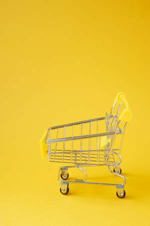 A food cart on a yellow background. Online shopping. A place for text.の写真素材