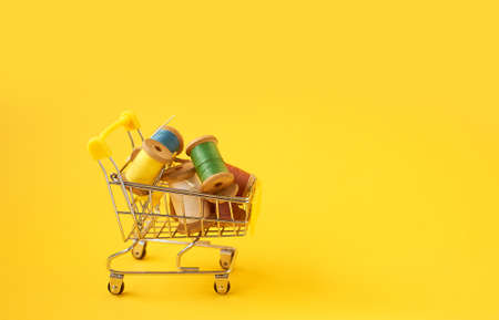 Colored coils with threads on a yellow background.Handicrafts and sewing.Shopping cart, online...
