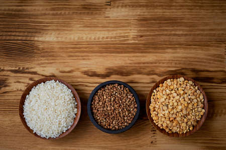 Useful food. The evils and the legumes. Buckwheat, rice, peas in flats on a wooden background. Simple and healthy food.の写真素材