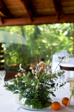 Composition of field herbs and cereals on the table in the restaurant in a transparent vase. White...