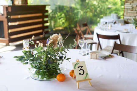 Composition of field herbs and cereals on the table in the restaurant in a transparent vase. White...