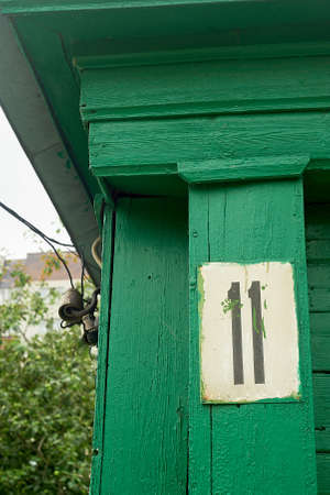 House number 11. An old sign on the wooden green facade of the house. Historic buildings.