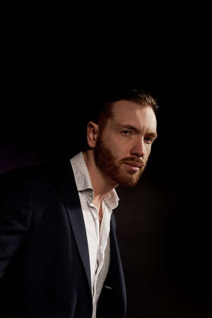 A man on a black background in a jacket and white shirt. Office style.