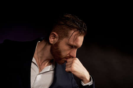 A man on a black background in a jacket and white shirt. Office style. Thinks about a difficult task