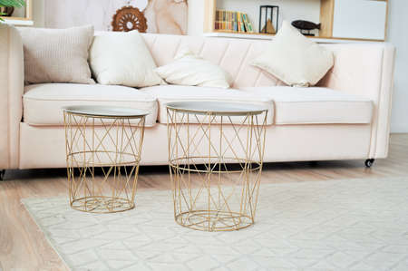 A bright and cozy living room with a sofa and iron round tables. Light room designの写真素材