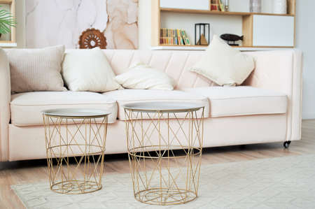 A bright and cozy living room with a sofa and iron round tables. Light room design