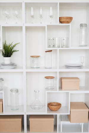 White open rack with glass glasses and jars. Plants and boxes. Decor of the kitchen or living room.の写真素材