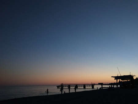 Sunset on the sea. Blue-orange. People and pier, contrasts.の写真素材
