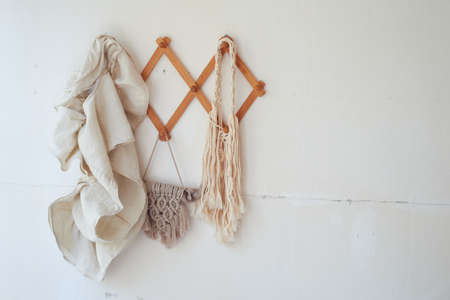 Decor items hang on a white wall on a wooden hanger. Macrame , towels. Rustic style.