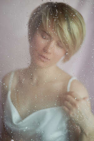 Portrait of a girl on a pink background with flowers. Tenderness and feminine. The sphere of beauty and womens health. Short haircut, blonde hairの写真素材