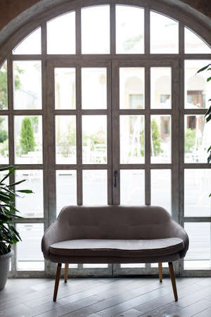 Sofa on the background of a window with a wooden frame and small glasses. Aesthetics and d cor