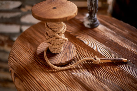 Wedding decoration in the Slavic style. A wooden reel with a strong rope and a pencil. An element of the table for notesの写真素材