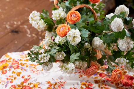 Wedding decoration in the Slavic style. Birch bark box with a flower arrangement in orange with ranunculi and greenery. Hay and a painted shawlの写真素材