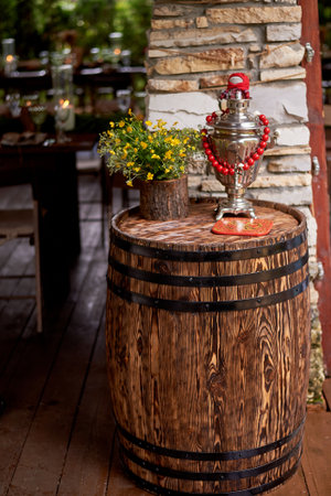 Wedding decoration in the Slavic style. An old barrel with a samovar and yellow flowersの写真素材