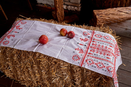Wedding decoration in the Slavic style. A white napkin embroidered with red thread and apples on a pile of hayの写真素材