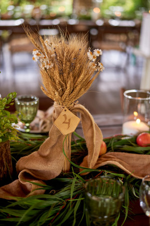 Wedding decoration in the Slavic style. Table number for guests and a bouquet of cerealsの写真素材