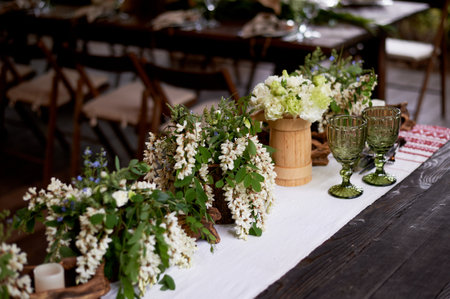 Banquet decoration in a simple rustic style with grass, greenery, simple objects and fabrics. Wedding table setting for guestsの写真素材