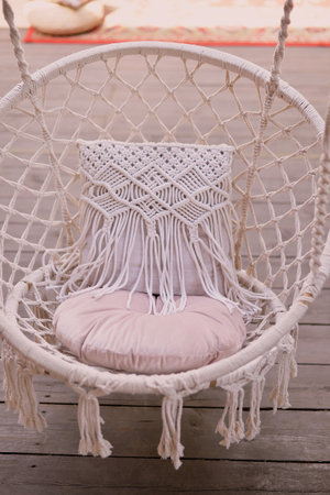 The swing is light wicker with a soft pillow in the style of macrome. Boho style, garden design.の写真素材