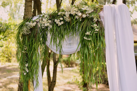 Arch for off-site registration. White chiffon and grass. Outdoor wedding.の写真素材
