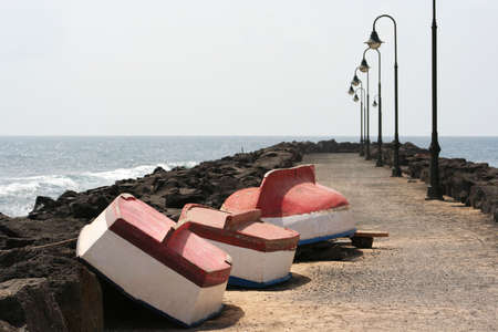 three small boats upturned on a jetty/breakwater for winter storageの写真素材