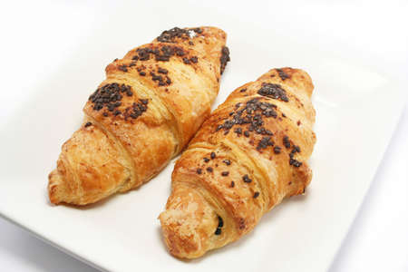two scrummy chocolate croissants on an off white plate, just waiting to be eaten.の写真素材