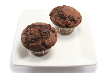 two delicious chocolate chip muffins on a square china plateの写真素材