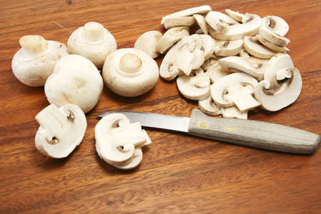 whole and sliced mushrooms on a wooden chopping board - close upの写真素材
