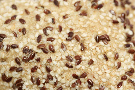 Toasted and raw sesame seeds on a bread roll - useful as backgroundの写真素材