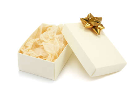 A open cream textured cardboard gift box with a gold metallic bow and crumpled tissue paper on a white backgroundの写真素材