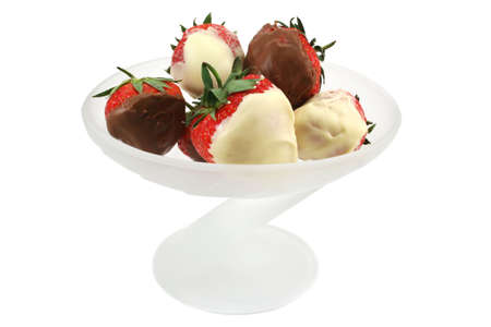 Fresh summer UK strawberries dipped in white and milk chocolate in a frosted glass dessert dishの写真素材