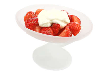 Sliced strawberries with sugar and creme fraiche but fresh cream is just as nice. In a tall frosted glass dessert bowl.の写真素材