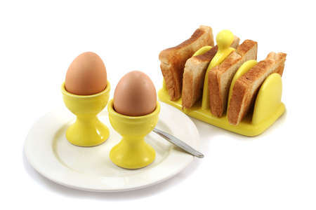 Two boiled eggs and toast with sunshine yellow egg cups and matching toast rackの写真素材