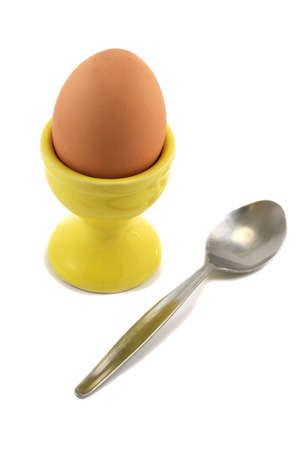 Boiled egg in a sunshine yellow egg cup with teaspoon, ready for eatingの写真素材