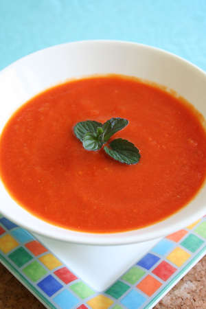 Homemade red pepper soup garnished with a sprig of black mint - lovely served hot or chilled for the summer.の写真素材