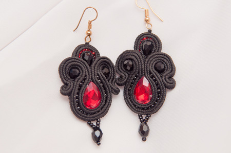black earrings with red glass on white backgroundの写真素材