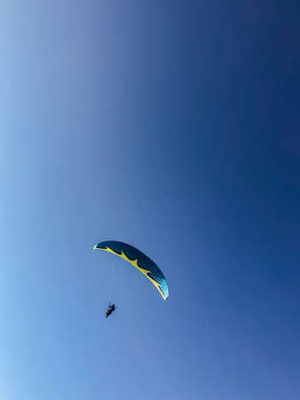 A man is engaged in paragliding. Parachute in the blue sky. Freedom.