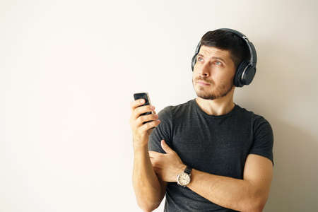 young man in a Cordless headphones with a smartphone in the handsの写真素材