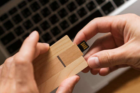 Wooden USB flash drive in the hands of big shot.の写真素材