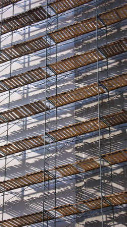 Scaffolding on the wall of multistorey buildings, covered the sunの写真素材