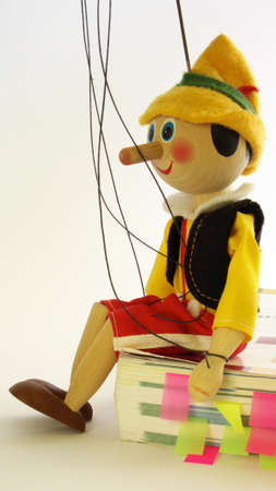 Wooden puppet sitting on a book with colored tabsの写真素材