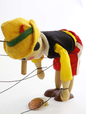 Wooden puppet bent over a pile of five euro cent coinsの写真素材