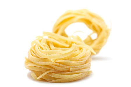 Two pieces of pasta - tagliatele. Close-up. Front rests, rear stands vertically. The background is blurred. Isolated on white backgroundの写真素材