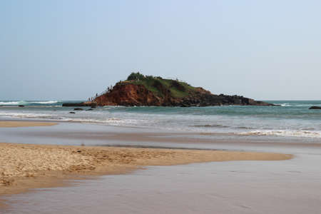 waves breaking on the hill in the middle of the sandy beachの写真素材