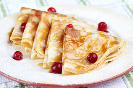Pancakes with cranberry berries and honey on a white plate