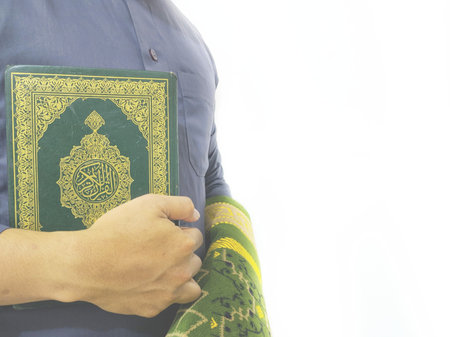 Close up of muslim man holding holy quran on white background