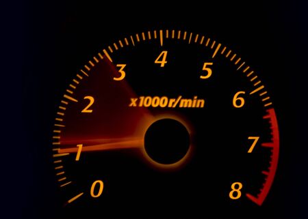 Car dashboard gauges illuminated at night, tachometer, speedometer