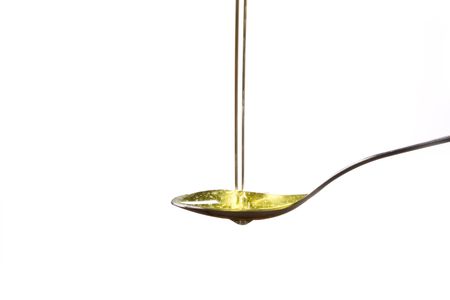 Olive oil poured  into a spoon 