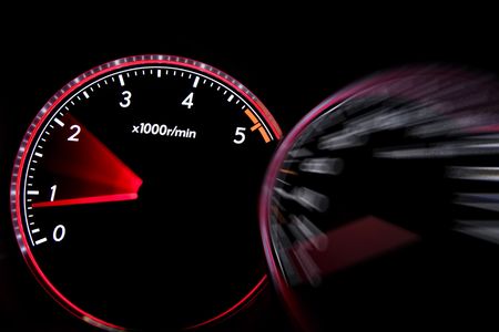 Car dashboard gauges illuminated at night, tachometer, speedometer